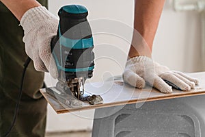 Man sawing laminate. Man is repairing the floor in the house, laminate flooring in the style of old boards