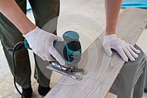 Man sawing laminate. Man is repairing the floor in the house, laminate flooring in the style of old boards