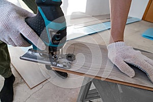 Man sawing laminate. Man is repairing the floor in the house, laminate flooring in the style of old boards