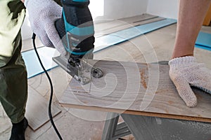 Man sawing laminate. Man is repairing the floor in the house, laminate flooring in the style of old boards