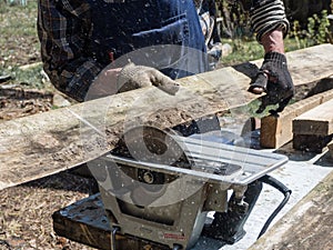 Man sawing wood circular saw, flying chips