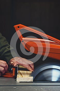 A man is sawing wood on a circular table saw