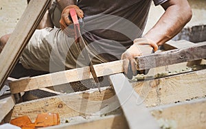 Man sawing wooden plank with a handsaw