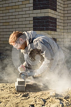 A man saws off paving stones with an angle grinder. Street work