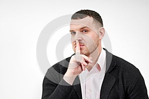 Man saying hush and be quiet with finger on lips gesture looking at camera