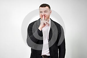 Man saying hush and be quiet with finger on lips gesture looking at camera