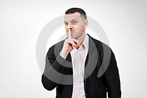 Man saying hush and be quiet with finger on lips gesture looking at camera