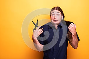 Man with scared look thinking of cutting hair with scissors