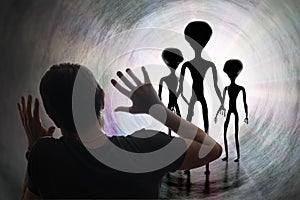 Man is scared of silhouettes of aliens in tunnel. Abduction and kidnapping by aliens concept.