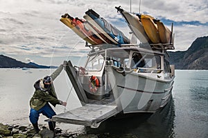 Man from scientific expedition park the vessel   on iceberg rock bay at wintertime to explore the island.