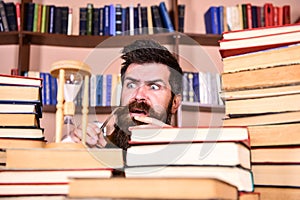 Man, scientist looks at hourglass. Man on serious and shocked face watching time is going over, bookshelves on