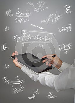 Man scientist or student holding tablet PC and working with various high school maths and science formulas.