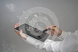 Man scientist with tablet pc and stylus or pen working with chemical formulas on gray background.