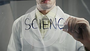 Man scientist writes the word `science` on the glass