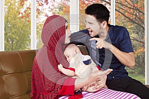 Man scolding his wife while holding baby photo