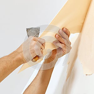 Man in with a scraper in the process of removing old wallpaper.