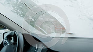 A man scrapes frost off the front window of his car on a cold winter