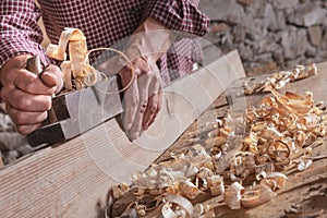 Man scraping curled wood scraps with hand plane tool