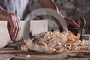 Man scraping curled wood scraps with hand plane tool