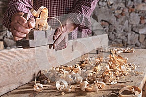 Man scraping curled wood scraps with hand plane tool