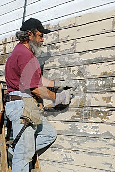 Man Scraping Paint from House