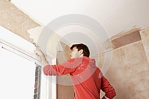 Man Scraping Paint Off Wall In Unrenovated Room