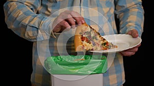 Man scraping with a plate a pizza into garbage bin