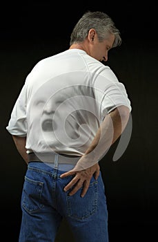 Man with screaming backache with wincing face pushing through his shirt where the pain is radiating from photo