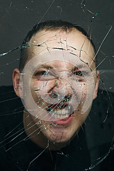 Man screaming through broken glass. Close up portrait