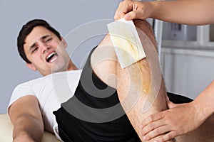 Therapist Waxing Man`s Leg With Wax Strip