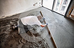 Man screeding floor in apartment during renovation.