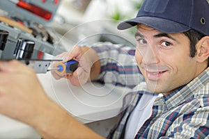 man screwing flathead screw into kitchen