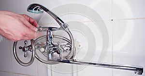 Man screwing the shower hose to the faucet. Hands of a plumber close-up.