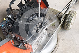 A man screws a bolt into a lawn mower. Lawn mower repair in the service