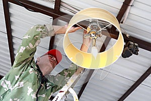 Man screws chandelier to ceiling of garage