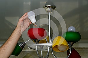 A man screws an LED lamp into a chandelier.