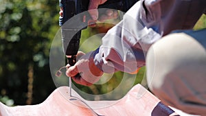 Man screws a screw into the roof. Stock footage. The professional worker works on installation of a roof of a roof by