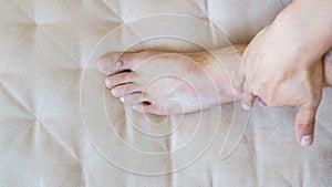 Man scrub the white medicine ointment cream on his bad injured ankle sitting on couch at home