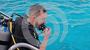 a man with scuba diving is sitting on board a yacht, preparing to dive, diving in the sea