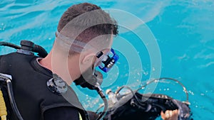 a man with scuba diving is sitting on board a yacht, preparing to dive, diving in the sea