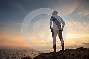 Man on the sea coast look on the sunset