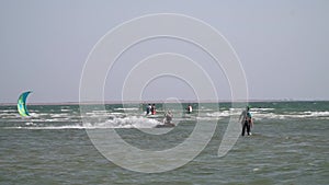 A man in the sea is kitesurfing, jumping and doing stunts