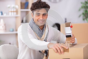 man sealing cardboard box with adhesive tape photo