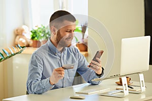 Man searching for products to buy on an online store on phone with credit card