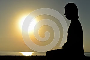 Man at seaside doing yoga at sunset