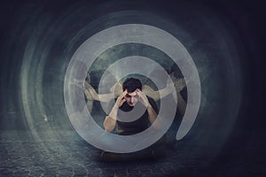 Man seated on the floor, hands to head, suffer split emotions into different inner personalities. Multipolar mental health