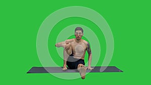 Man in Seated Marichyasana yoga pose stretching leg and spine exercise on a Green Screen, Chroma Key.