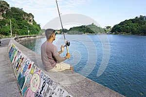 Man on seawall on vacation fishing