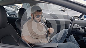 Man securely fastening seat belt in modern car interior