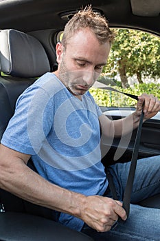 man securing seat belt in car